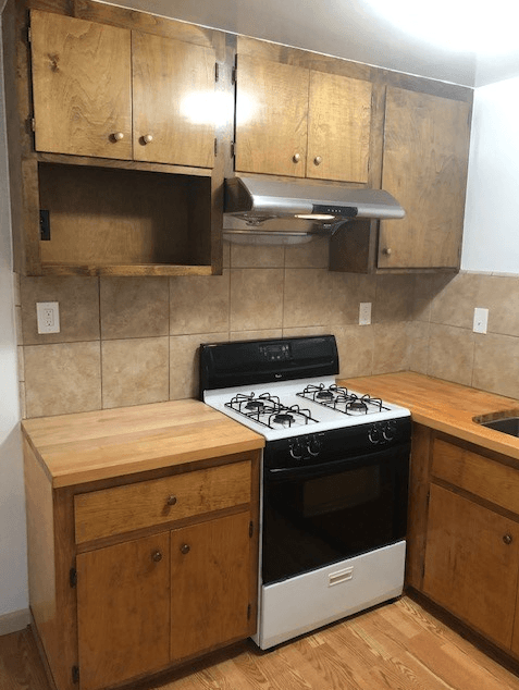 A kitchen with a stove and wooden cabinets.