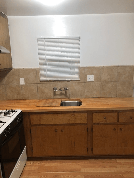 A kitchen with a stove, sink, and cabinets.