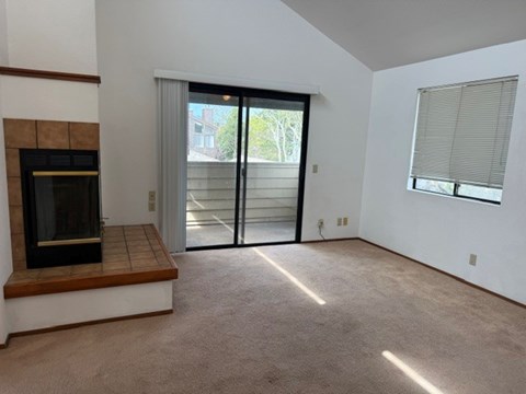 A room with a fireplace and sliding glass doors leading to a balcony.