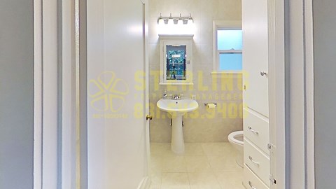 A bathroom with a white toilet and a window showing a view of the ocean.