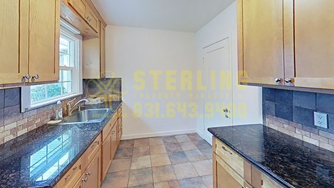 A kitchen with wooden cabinets and black countertops.