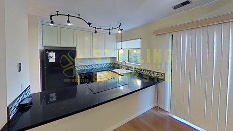 A modern kitchen with a black countertop and a large window.