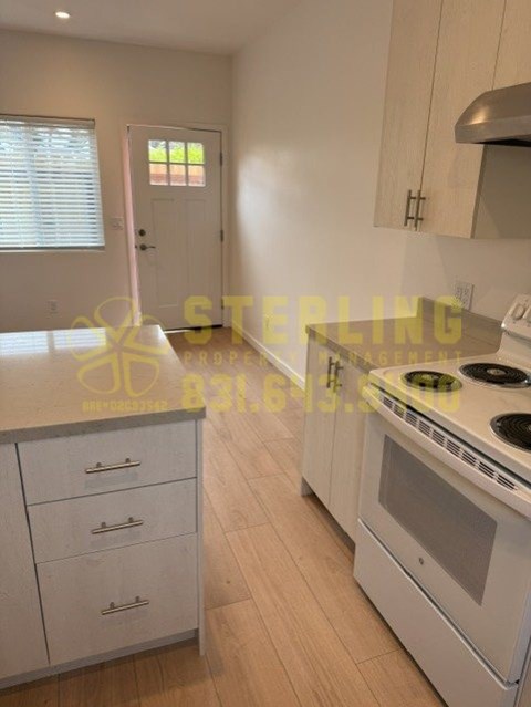 A kitchen with white cabinets and a stove top oven.