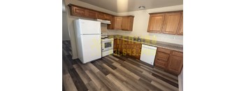 A kitchen with a white fridge and wooden cabinets.