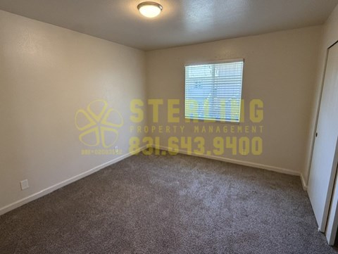 A room with a carpeted floor and a window with blinds.