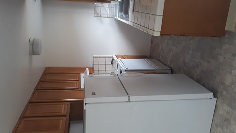 A white refrigerator is in a kitchen with brown cabinets.