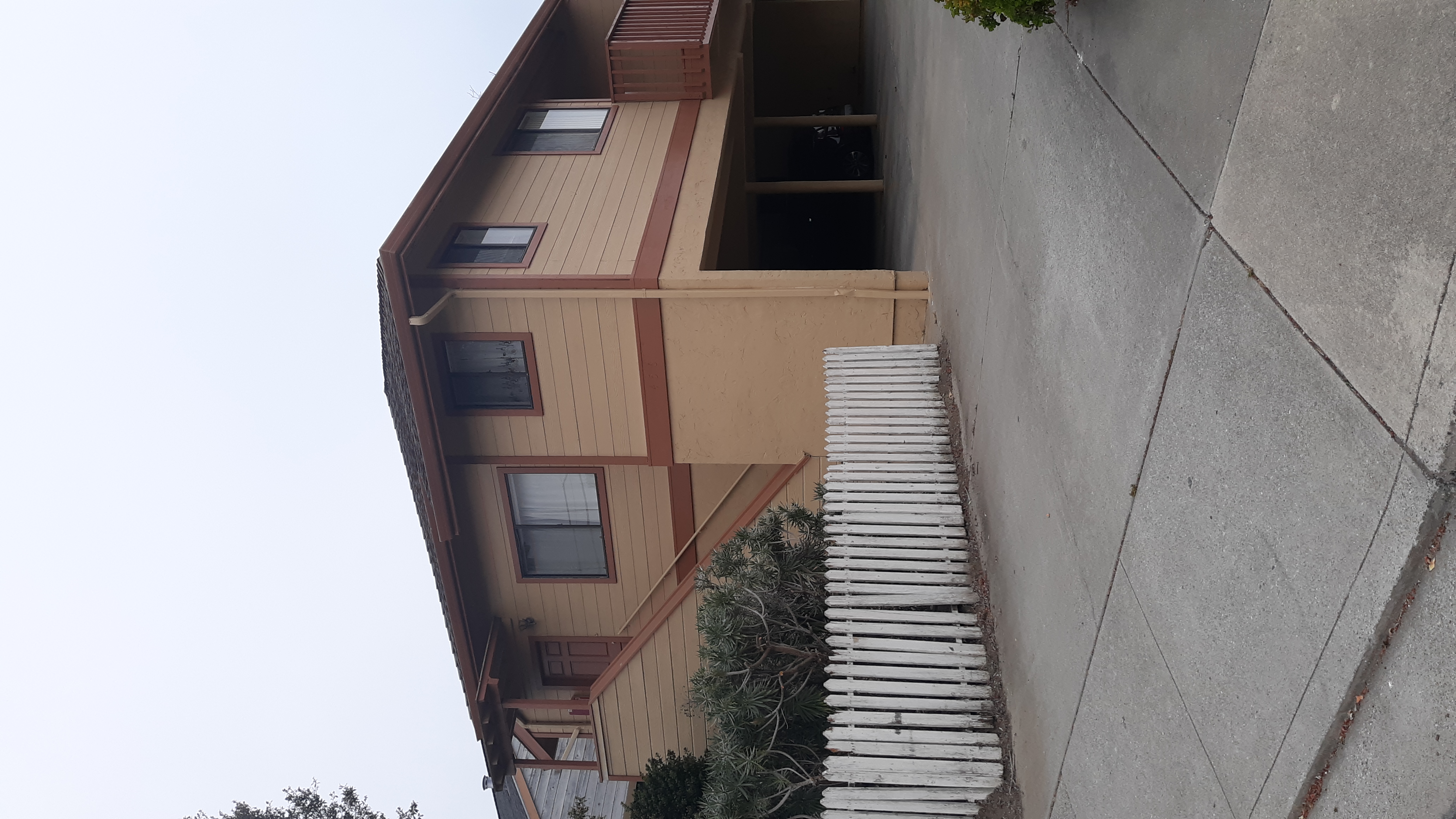 A building with a brown and tan exterior and a white staircase.