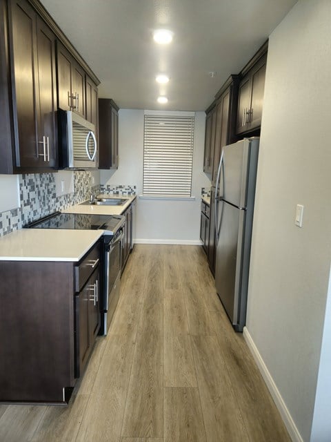 A kitchen with dark wood cabinets and a white countertop.