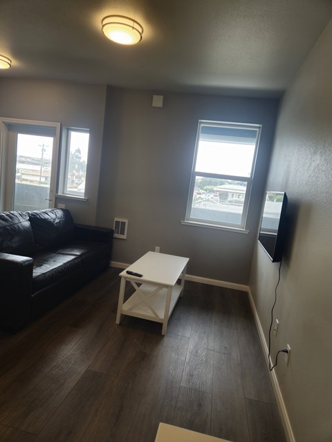 A living room with a black couch and a white coffee table.