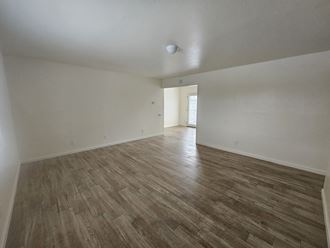 the living room and dining room of an apartment with wood flooring