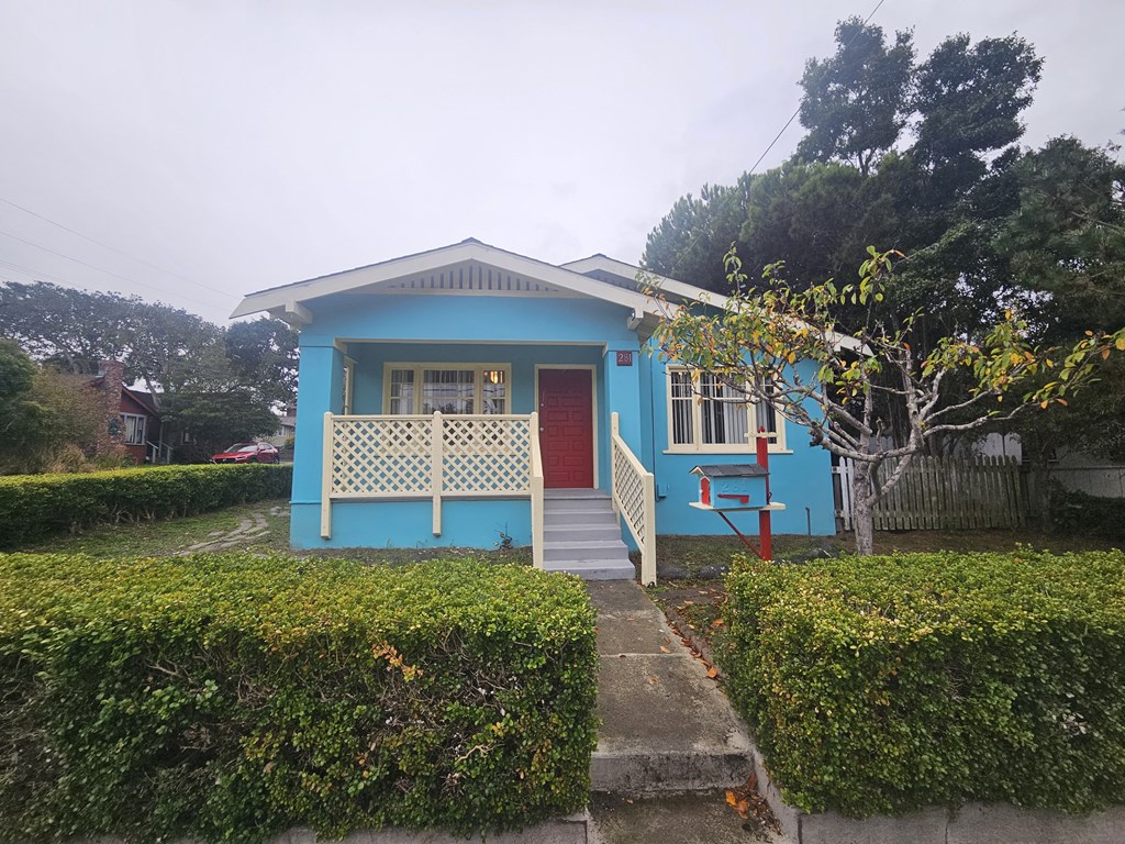 a small blue house with a porch and a red door