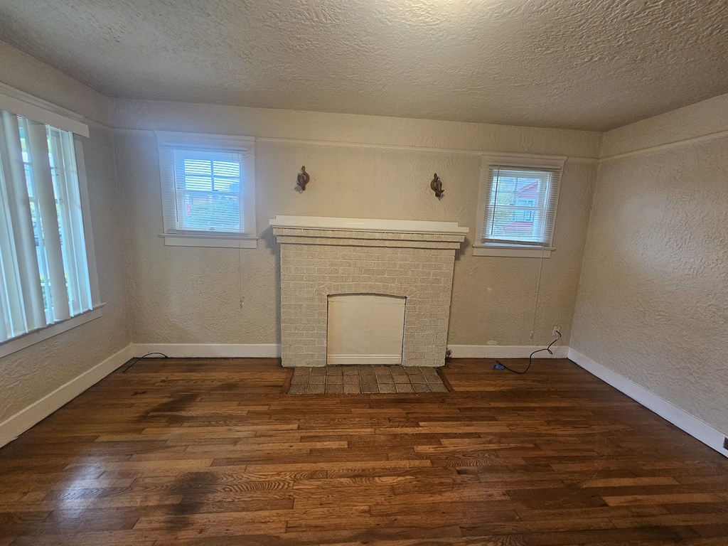 the living room of a house with a fireplace and wooden floors