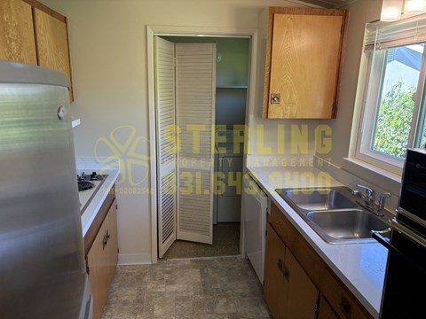 A kitchen with a refrigerator, sink, and cabinets.