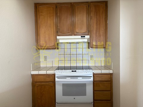 A kitchen with wooden cabinets and a white stove top oven.