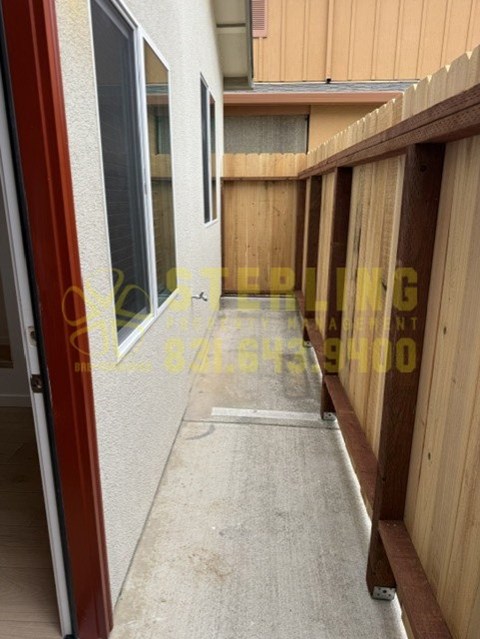 A view of a balcony with a red door and wooden fence.