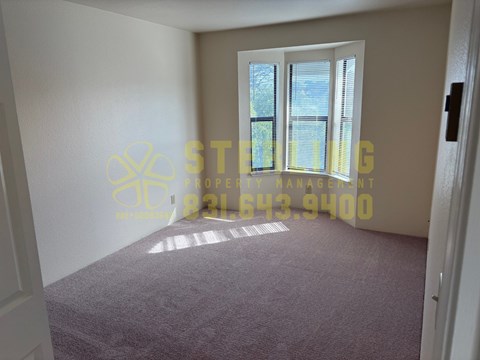 A room with a carpeted floor and a window with blinds.