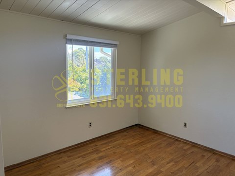 A room with a window and a wooden floor.