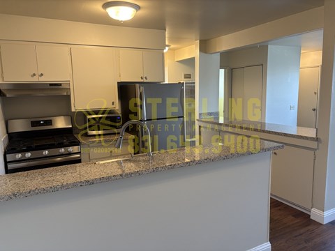 A kitchen with a granite countertop and a refrigerator.