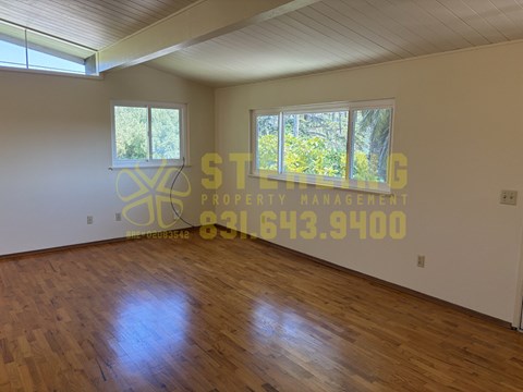 A room with wooden floors and a window with a view of trees.