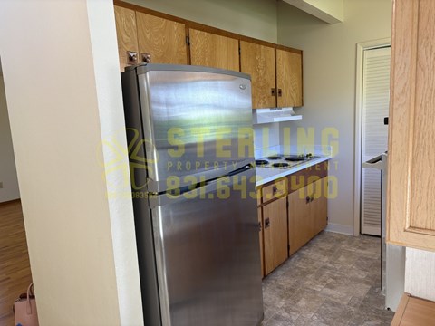 A kitchen with a refrigerator, cabinets, and a countertop.