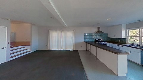 an empty kitchen with white cabinets and a counter top
