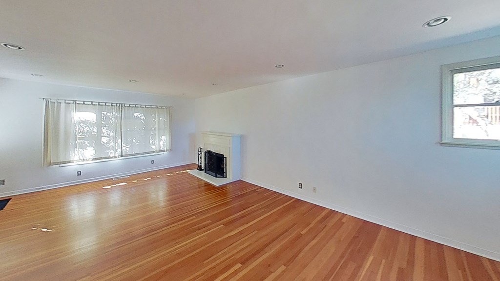 an empty living room with wood floors and a fireplace