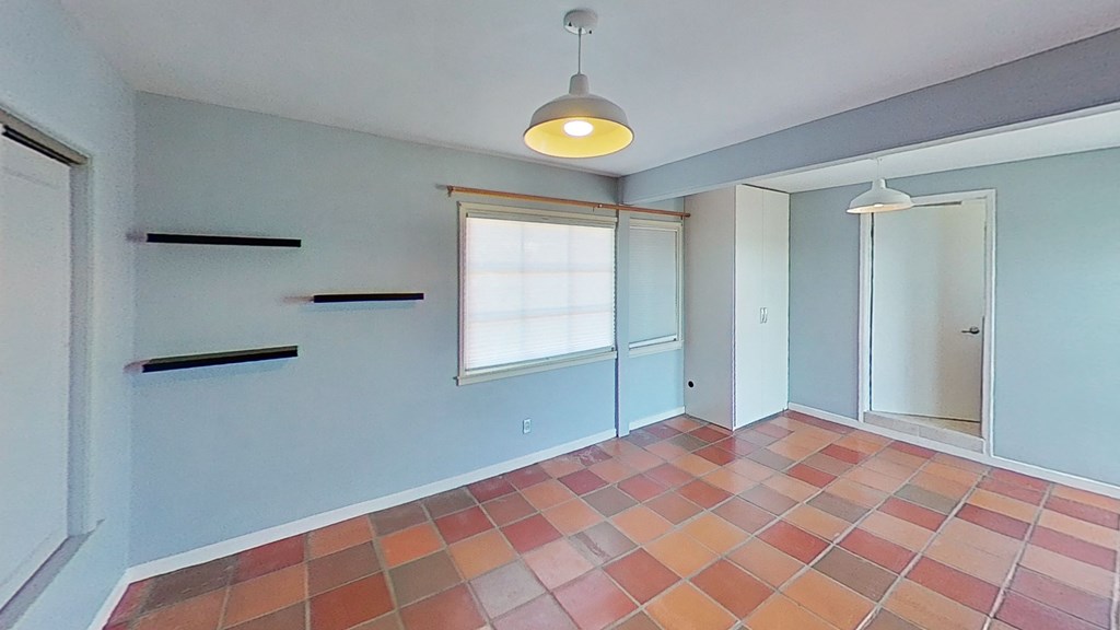 an empty living room with blue walls and a orange and white tiled floor