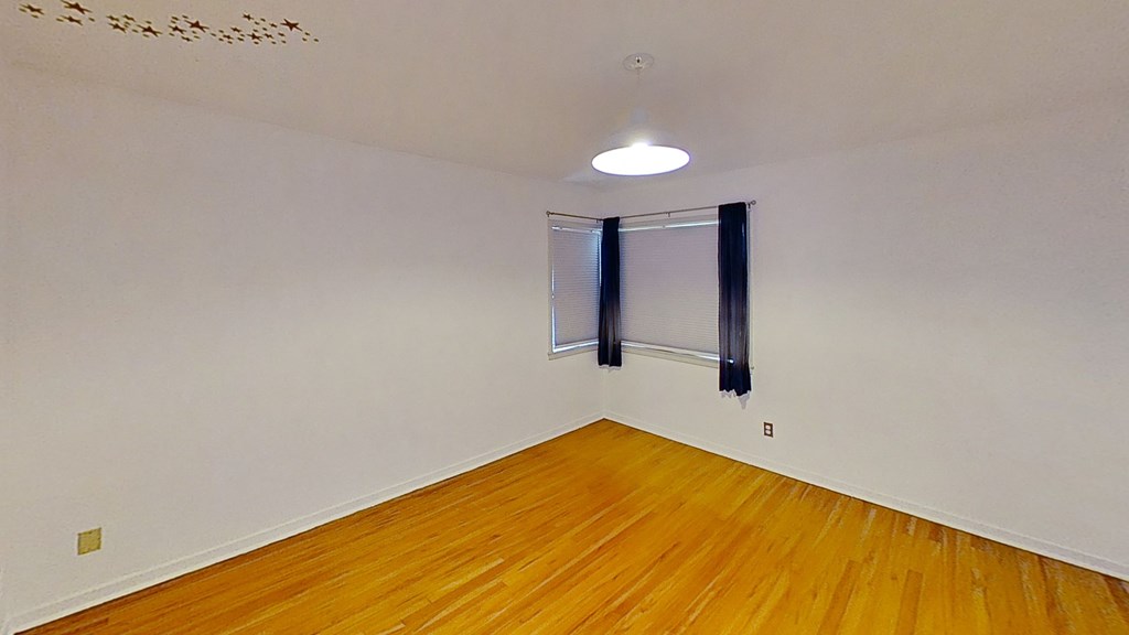the living room of an empty house with wood floors and a window