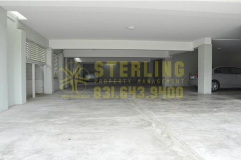 A spacious garage with a sign that reads "STERLING PROPERTY MANAGEMENT" and a phone number.
