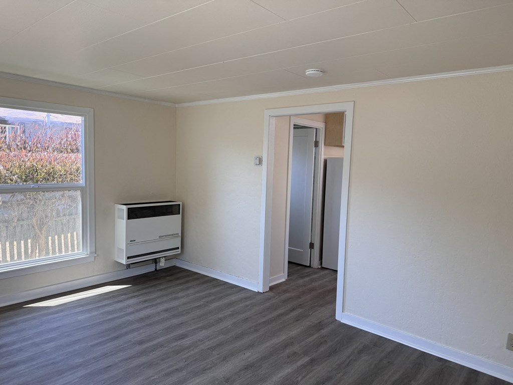 an empty living room with a large window and a tv