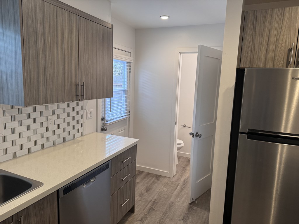 A kitchen with a stainless steel refrigerator and a white counter top.