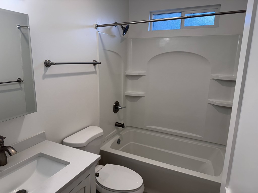 A white bathroom with a toilet, sink, and bathtub.