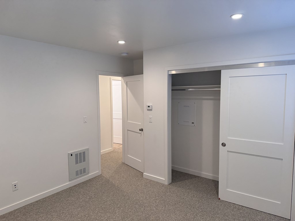 A white door is open to a small room with a white wall and a white door.
