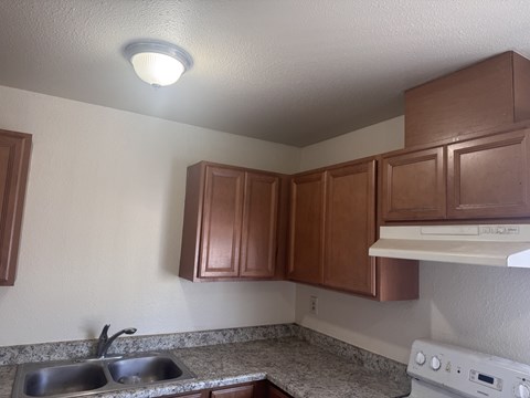 A kitchen with brown cabinets and a white stove.