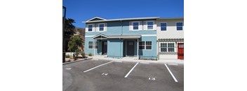 A blue building with a parking lot in front.