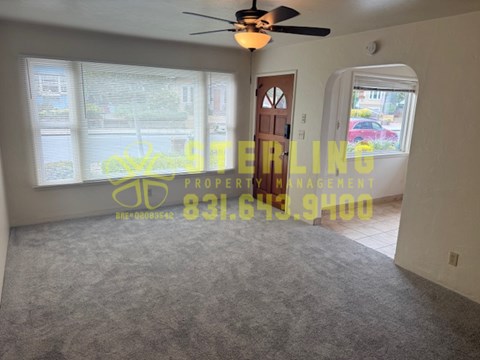 A room with a carpet floor and a ceiling fan.