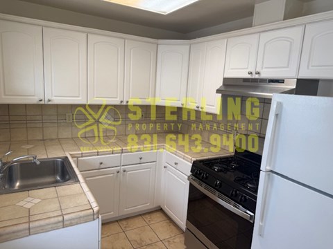 A kitchen with white cabinets and a stove top oven.