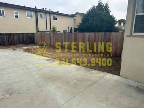 A Sterling Property Management sign is on a fence in front of a house.