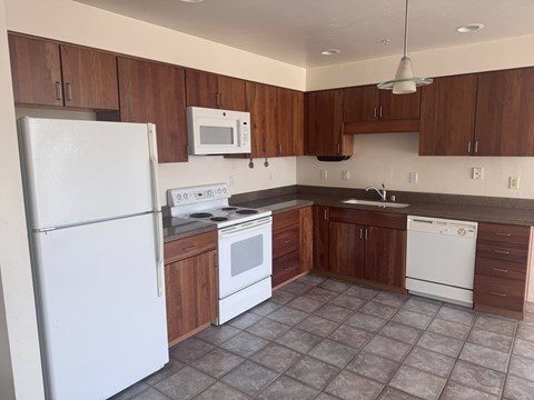 A kitchen with white appliances and brown cabinets.