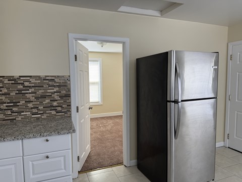 A black refrigerator is in a kitchen with a white door.