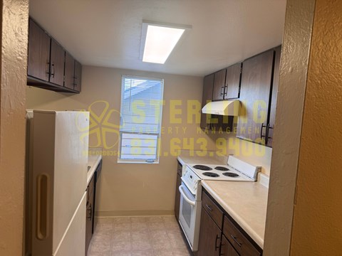 A kitchen with a stove top oven and a window with blinds.