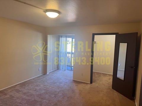 A room with a carpet floor and a door leading to a balcony.