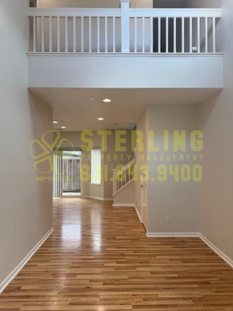 A hallway with wooden floors and a balcony on the second floor.