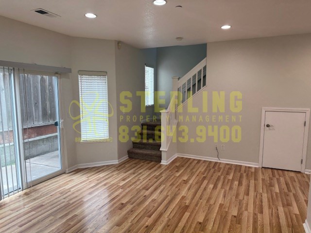 A room with wooden flooring and a staircase leading to another room.