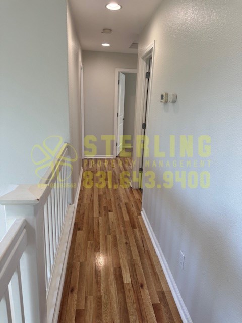 A long hallway with wood floors and white walls.