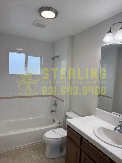A white toilet sits in a bathroom next to a sink.