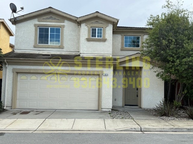 A house with a garage and a tree in front.