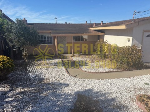 A house with a gravel driveway and a garden in front.
