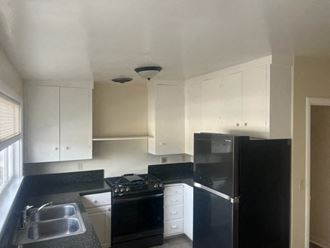 an empty kitchen with black appliances and white cabinets