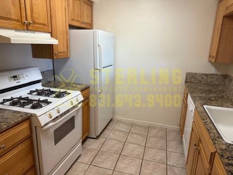 A kitchen with a stove, refrigerator, and cabinets.
